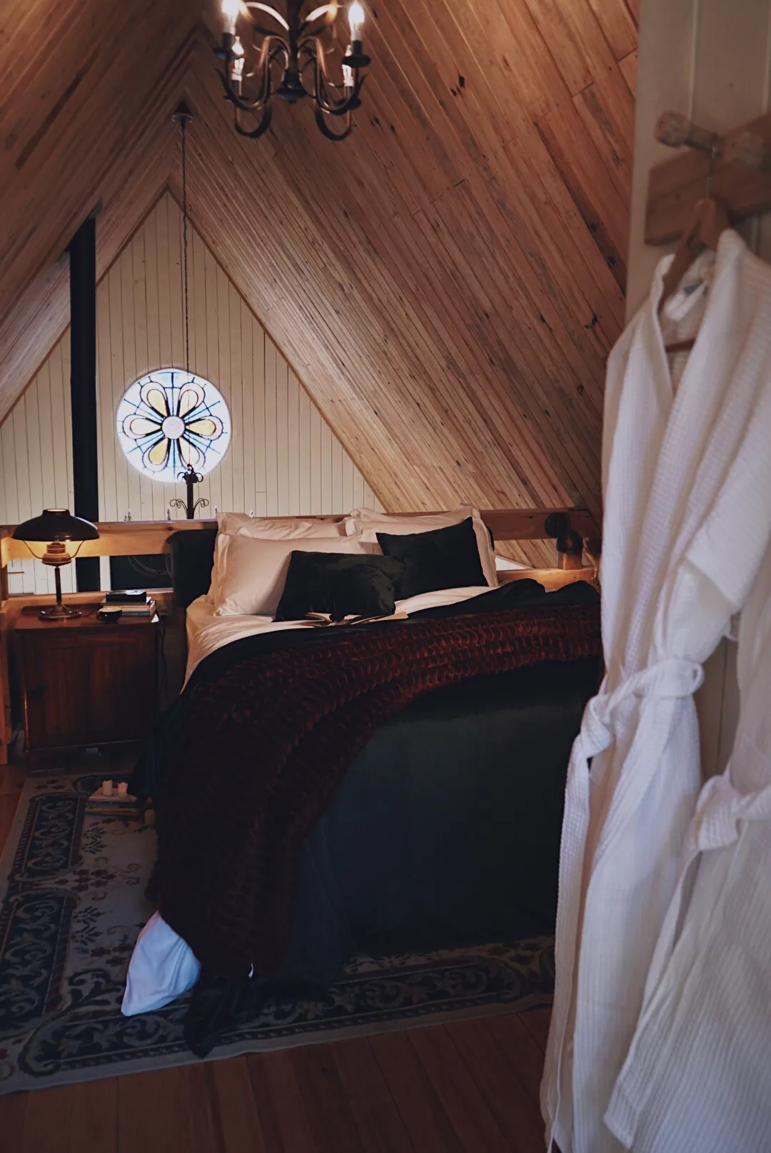 Quarto sob o telhado em A, com lustre e cama de casal